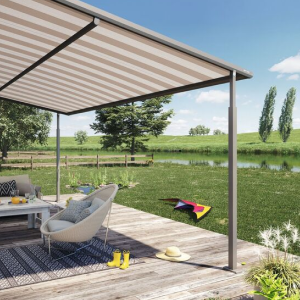 A terrace with a striped awning, outdoor furniture, and a green landscape by a water body.