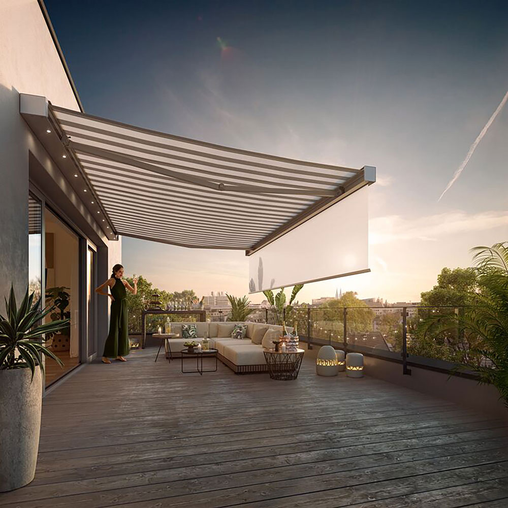 A spacious terrace with a large awning casting shadows, greenery in planters, and a comfortable seating area.