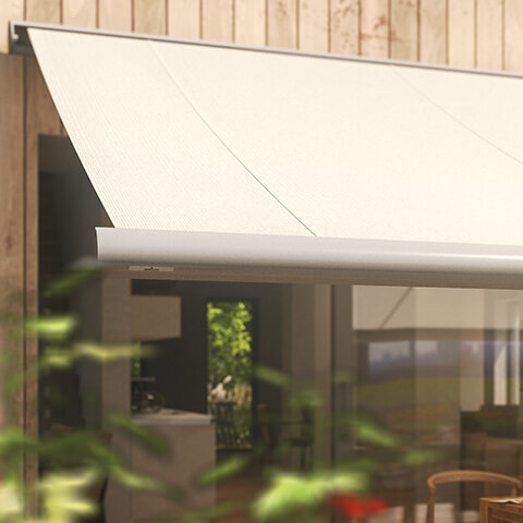 Awning with a light fabric design mounted on a wooden structure, partially obscured by green foliage.