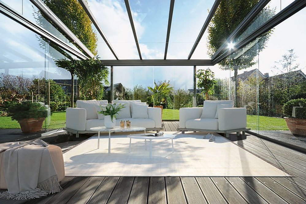 A bright, modern space with a glass structure, featuring white seating and a light rug. A bright, modern space with a glass structure, featuring white seating and a light rug.