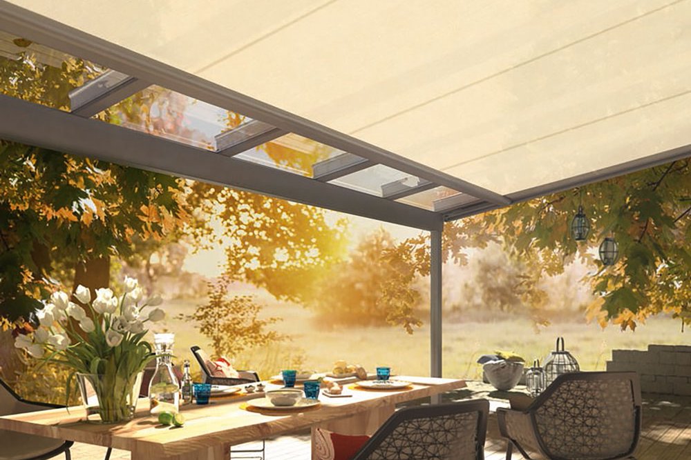 A tranquil outdoor dining area with a light-coloured cover and wooden table surrounded by chairs and greenery.