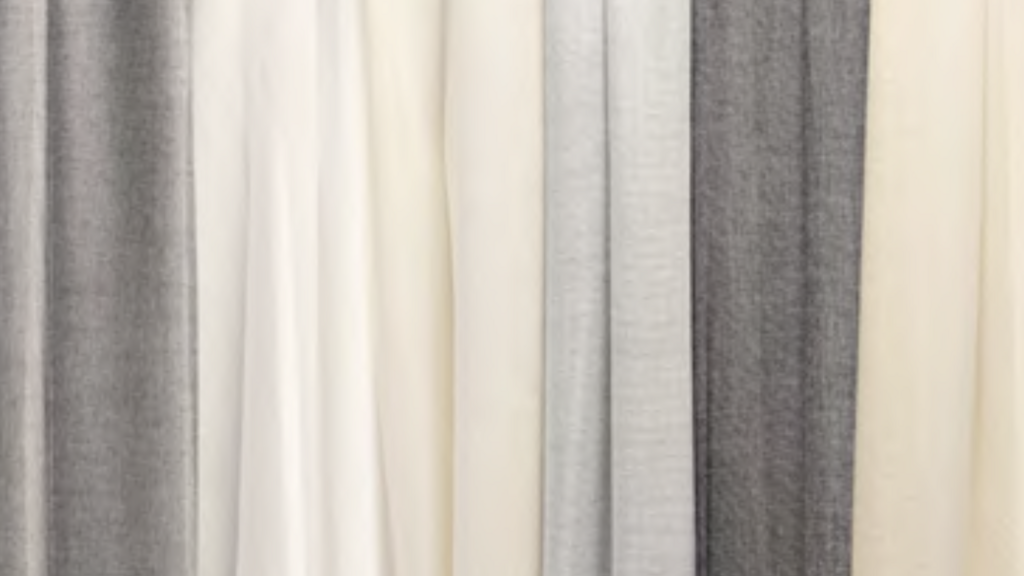 A series of vertical fabric panels in varying shades of grey and white.