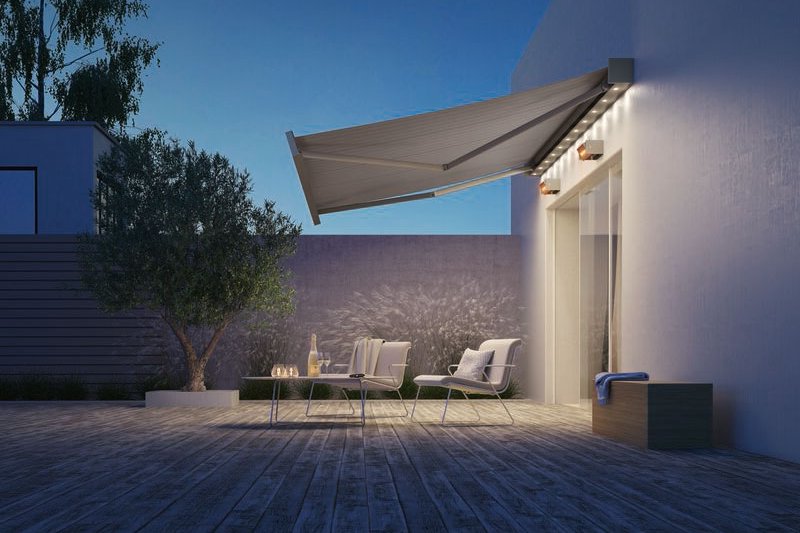 A modern terrace featuring a large awning, outdoor seating, and a calming evening atmosphere.