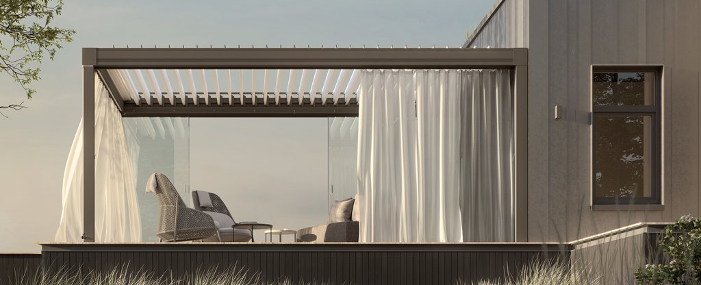 A modern terrace with a grey structure, glass panels, and white drapes, surrounded by green foliage and flowers.