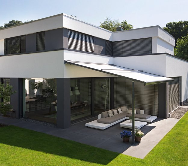 Modern house with a flat roof, large windows, and a covered terrace area. Dominant colours: white and grey. 