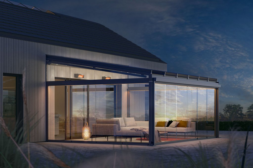 Modern winter garden with glass walls, a sleek roof, and outdoor seating illuminated at dusk.