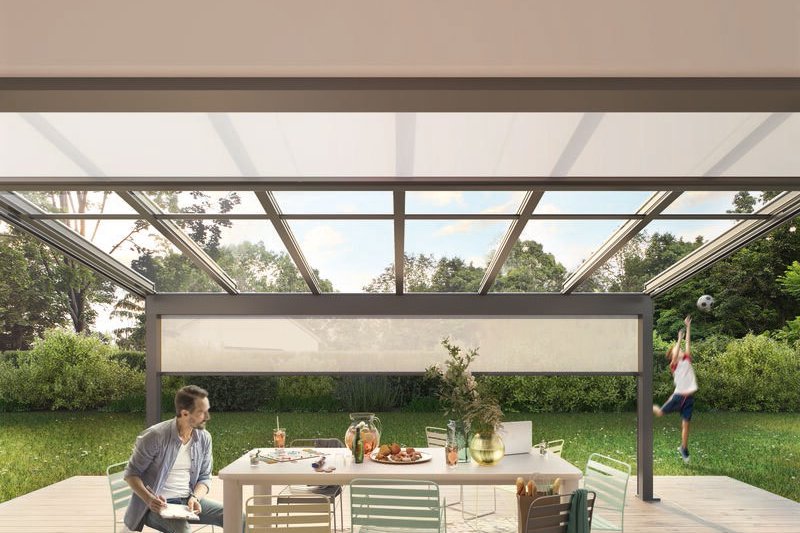 Elegant outdoor dining area under a structure with a large glass ceiling and surrounding greenery. Elegant outdoor dining area under a structure with a large glass ceiling and surrounding greenery.
