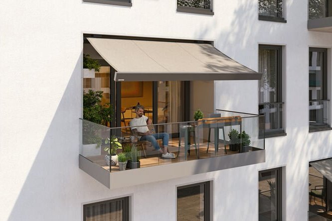 A modern balcony featuring a awning, glass railing, and a comfortable seating area.