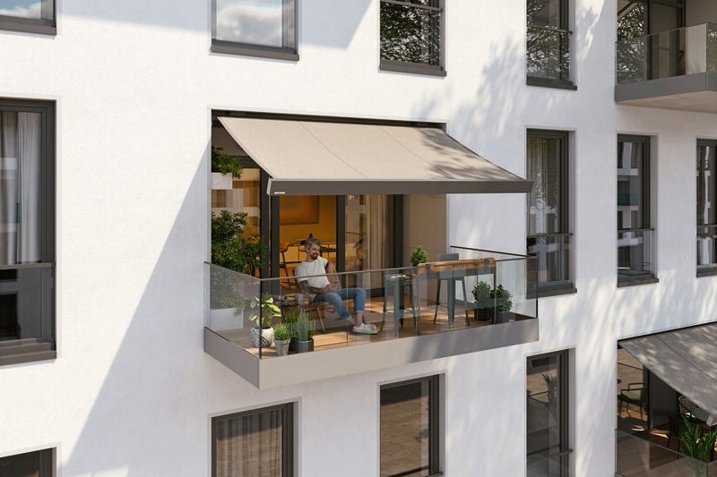 A modern balcony featuring a awning, glass railing, and a comfortable seating area. A modern balcony featuring a awning, glass railing, and a comfortable seating area.