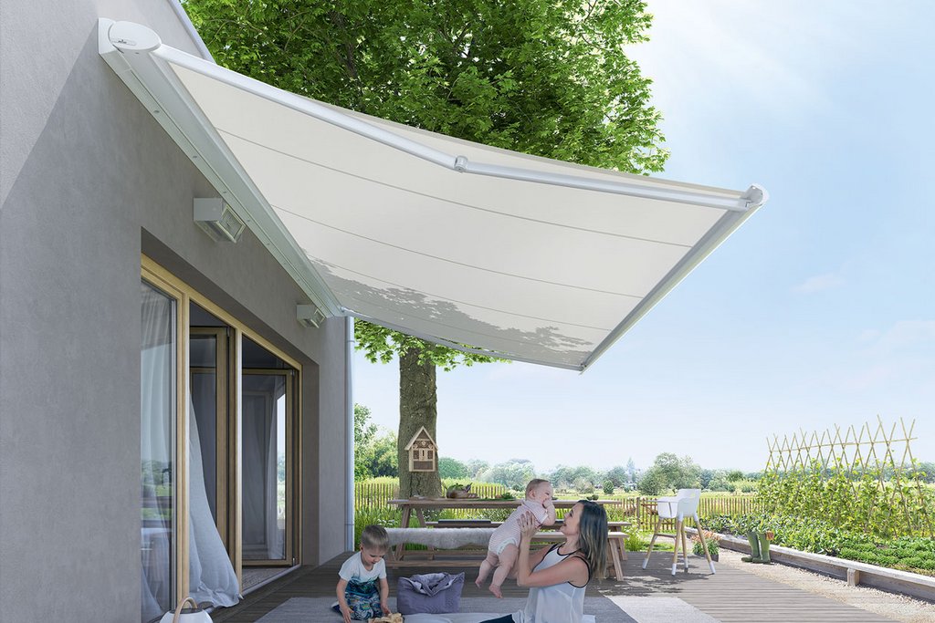 A white awning casting shade over a wooden terrace with a green tree in the background.