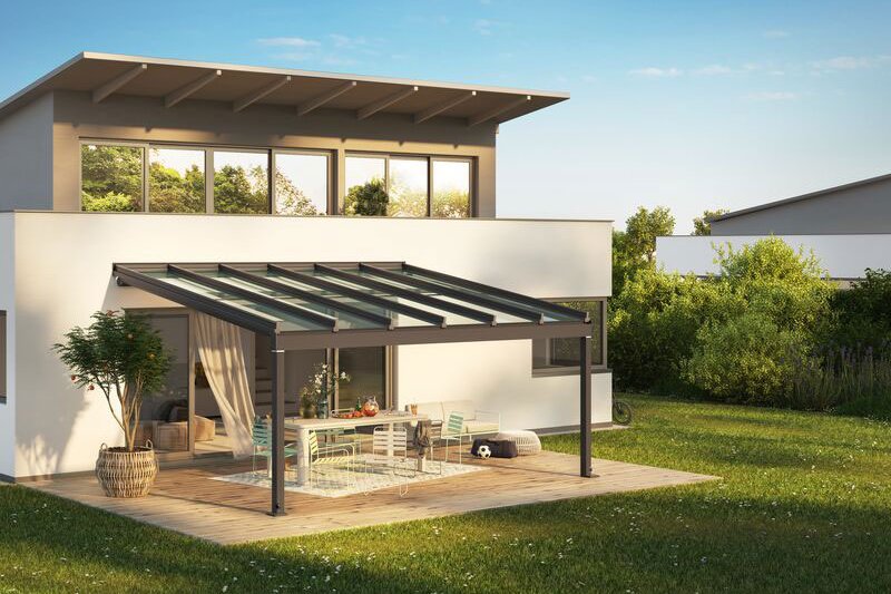 A modern house with a flat roof, featuring a glass-covered terrace and surrounding greenery.