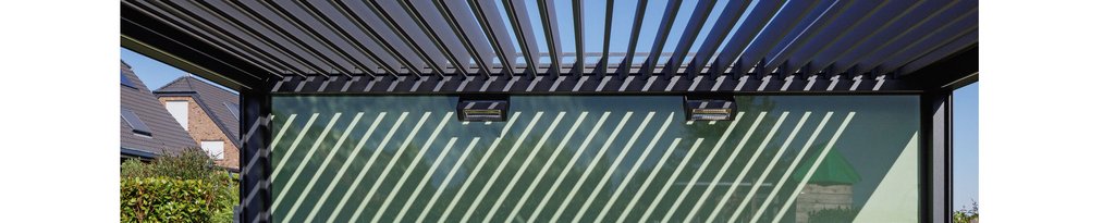 Shadows created by a slatted structure over a glass wall, with a blue sky visible above. Shadows created by a slatted structure over a glass wall, with a blue sky visible above.