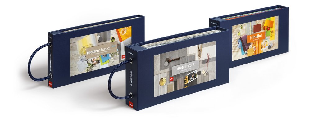 Three rectangular booklets with dark blue covers and various colourful designs on the front. Three rectangular booklets with dark blue covers and various colourful designs on the front.