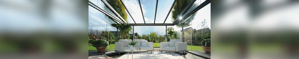 A bright and modern terrace situation featuring a glass structure and minimalist furniture.