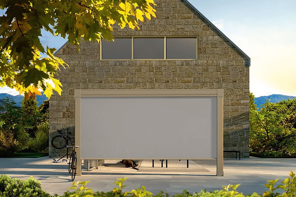 A modern building with a flat-roofed extension, featuring a white panel and surrounded by greenery.
