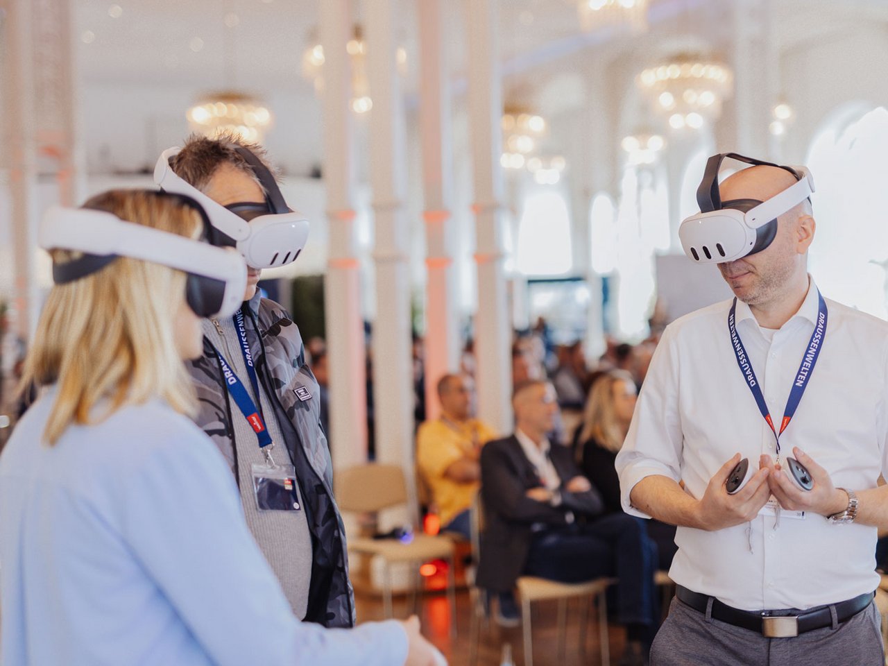 Three individuals wearing VR headsets in a conference setting, engaged in discussion.