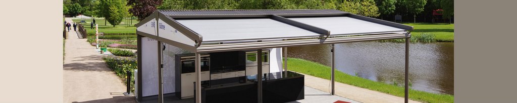 A terrace situation featuring an overhead structure with retractable awnings beside a waterway in a park. A terrace situation featuring an overhead structure with retractable awnings beside a waterway in a park.