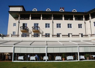 A building with balconies and a covered terrace, surrounded by a blue sky. 