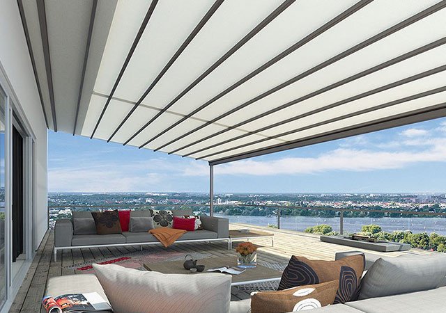 A modern terrace with a large overhanging awning, offering a view of the landscape and sky.