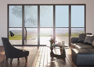 A modern living room with large glass panels showcasing an outdoor view, featuring a stylish chair and a coffee table. 