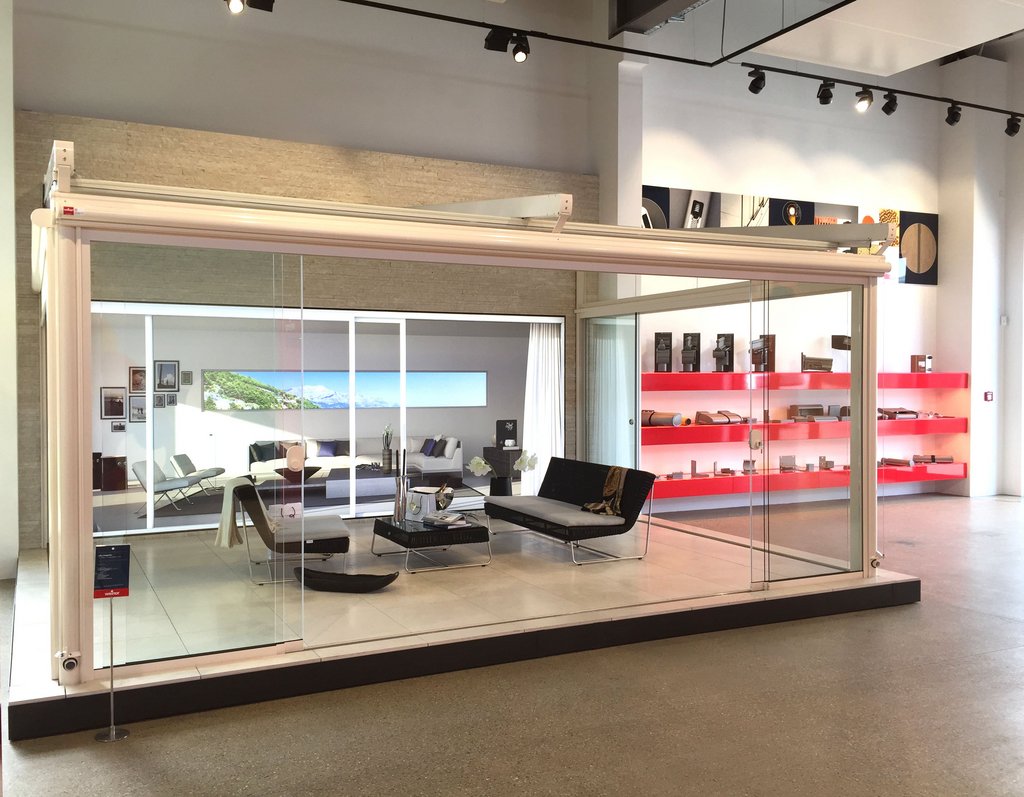 Showroom display featuring a glass structure with modern furnishings and a light aesthetic.