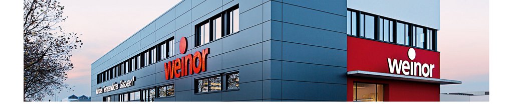 Modern building facade with large windows and a red company sign.
