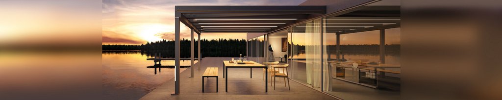 Modern terrace with an outdoor seating area, glass walls, and a sunset over a calm water body.