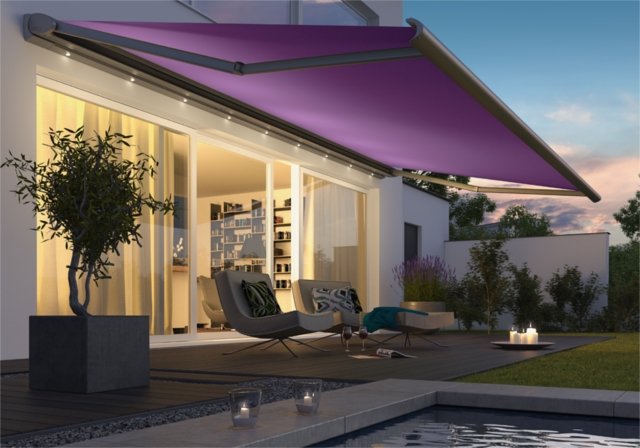 A purple awning extends over a terrace with modern furniture and a relaxing atmosphere in the evening light.