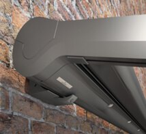 A grey awning box mounted on a textured brick wall.