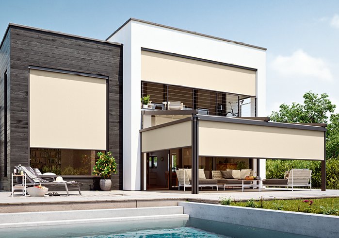 Modern house with beige awnings and a shaded area over the terrace, surrounded by greenery and a swimming pool.