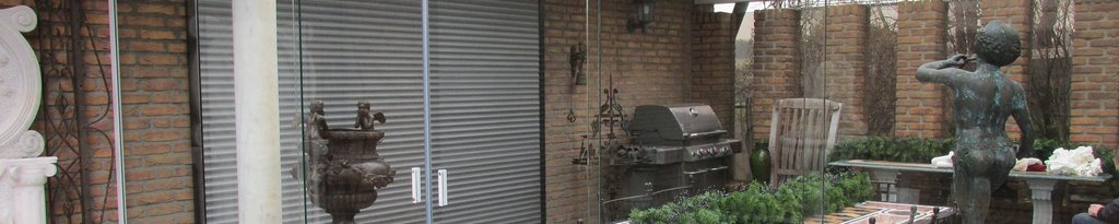 Terrassensituation mit einer Mischung aus Pflanzen, einer Statue und einem Grill im Hintergrund. Dominant sind Grautöne.