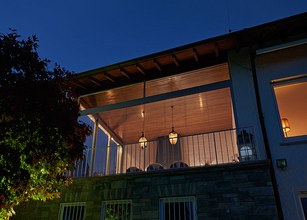 A well-lit terrace with a wooden roof and decorative hanging lights at night. 