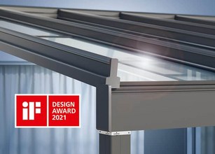 Detail of a grey structure featuring a glass roof design, with an award logo in the bottom left corner. 