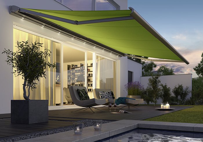 A green awning extended over a modern terrace with seating and a swimming pool.
